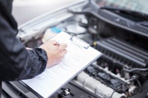 A checklist for car insurance compliance, featuring a man meticulously documenting maintenance and engine control tasks. This image captures the essence of vehicle inspection and maintenance, with the male hand symbolizing attention to detail and care.