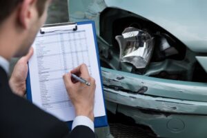 A side view showcasing an insurance agent meticulously noting details on a clipboard while inspecting a car post-accident. 