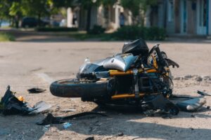 The motorcycle lies on the road after a collision. It's a severe accident, shown in close-up. The bike is damaged, indicating a traffic accident.