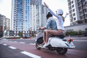 Back view of a beautiful young couple in helmets riding a scooter. 