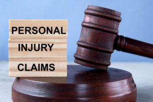 Wooden cubes spelling out "PERSONAL INJURY CLAIMS" positioned against the backdrop of a judge's gavel and stand.