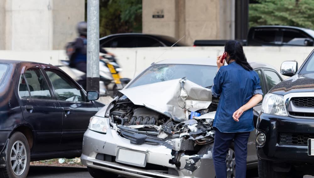 An Asian woman calls for help and urgently requests an insurance agent's immediate attention at the accident scene after cars crashed on the road.