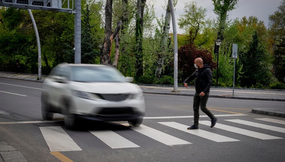 Pedestrian walking on zebra crossing and a driving car failing to stop in blurred motion.