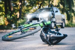 Close-up of a bicycling helmet fallen on the asphalt next to a bicycle after car accident on the road.