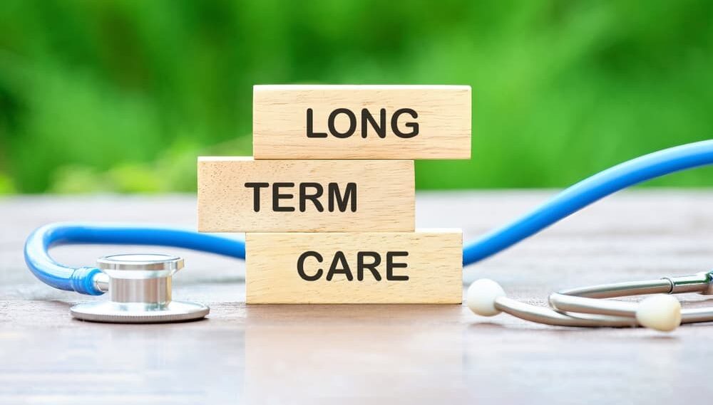 LONG TERM CARE text on wooden blocks on a green background