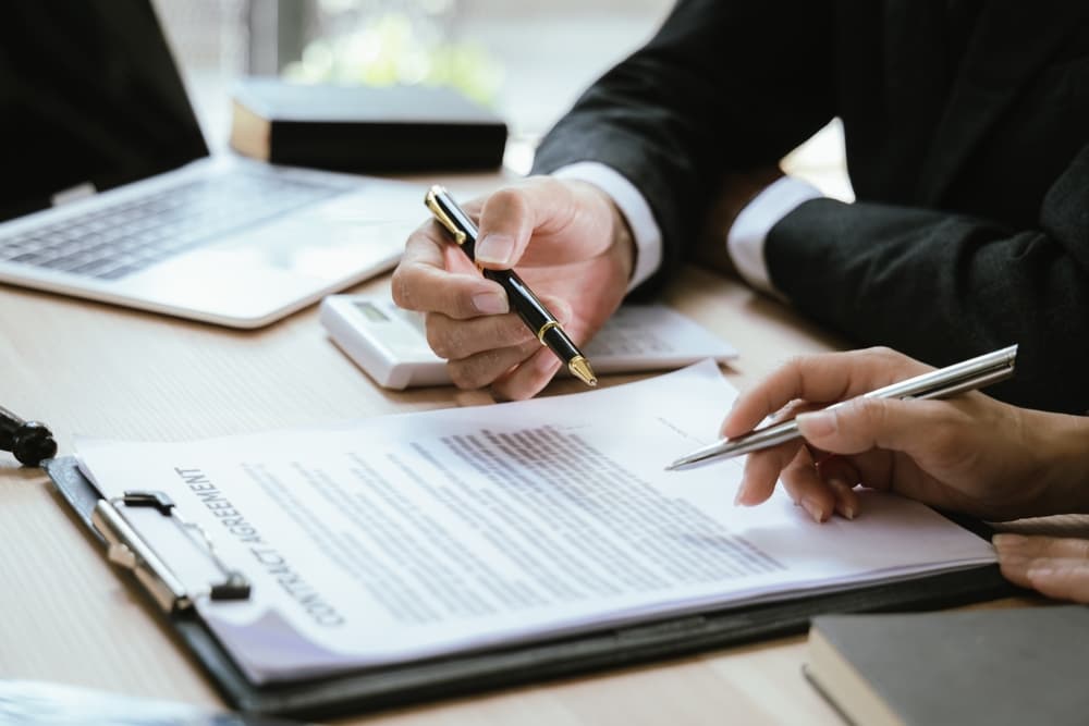 Abogados revisando y firmando un acuerdo legal, representando el proceso de reclamaciones y demandas judiciales.